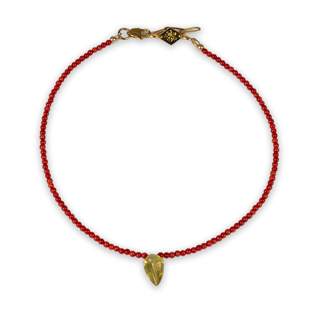 Red beaded necklace with lemon quartz shell with a gold clasp on a white background