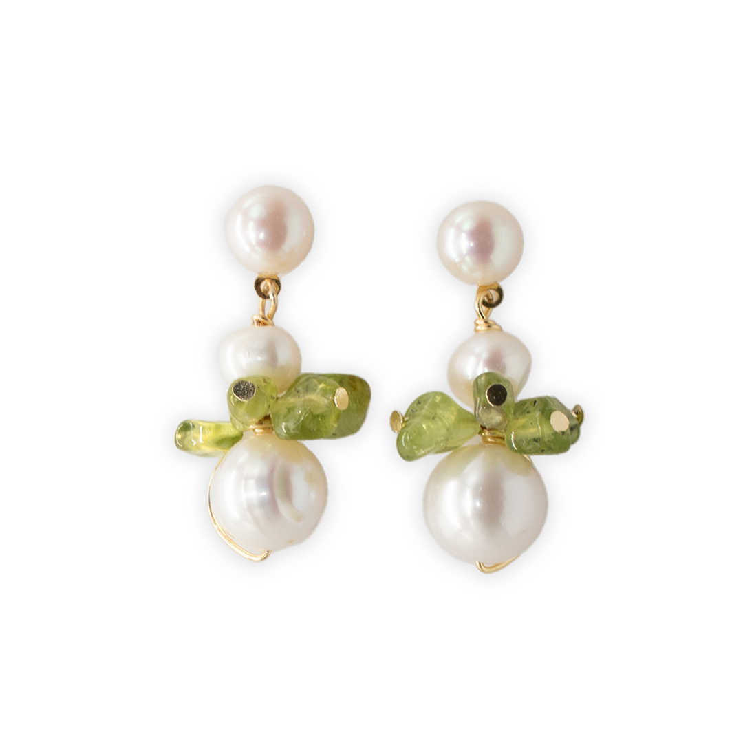 A pair of gold-tone dangle earrings featuring white baroque pearls and green gemstone peridot, displayed on a solid white background.