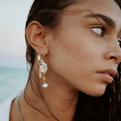Beautiful model wearing long statement earrings on the beach at sunset